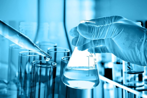 Lab person testing the water in a flask