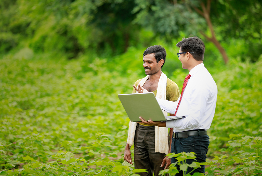 Techie with a laptop talking to a farmer in a field