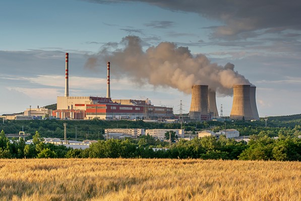 Factory with gases being emitted near a field