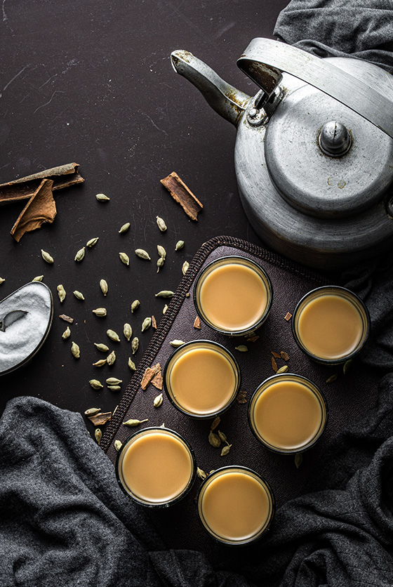 Indian chai in glass cups next to a metal kettle